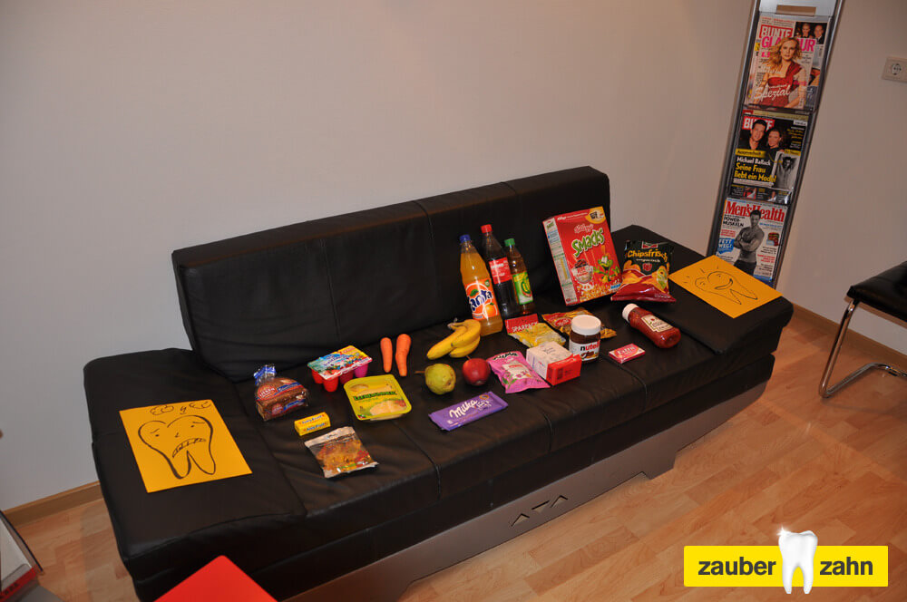 Auswahl verschiedener Lebensmittel und Getränke auf einem schwarzen Sofa.