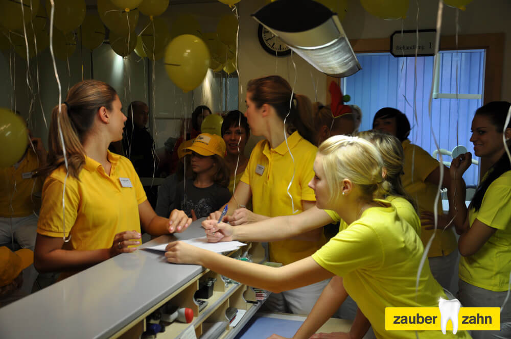 Mehrere Mitarbeiterinnen in gelben Poloshirts stehen gemeinsam an einer Theke.