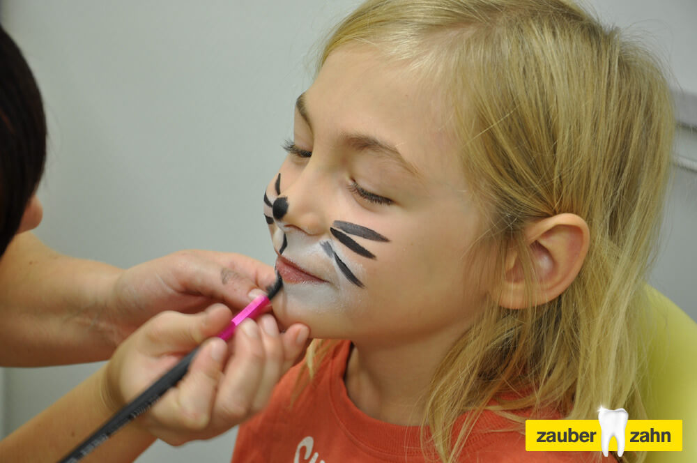 Kind bekommt eine Katzenbemalung ins Gesicht gemalt.