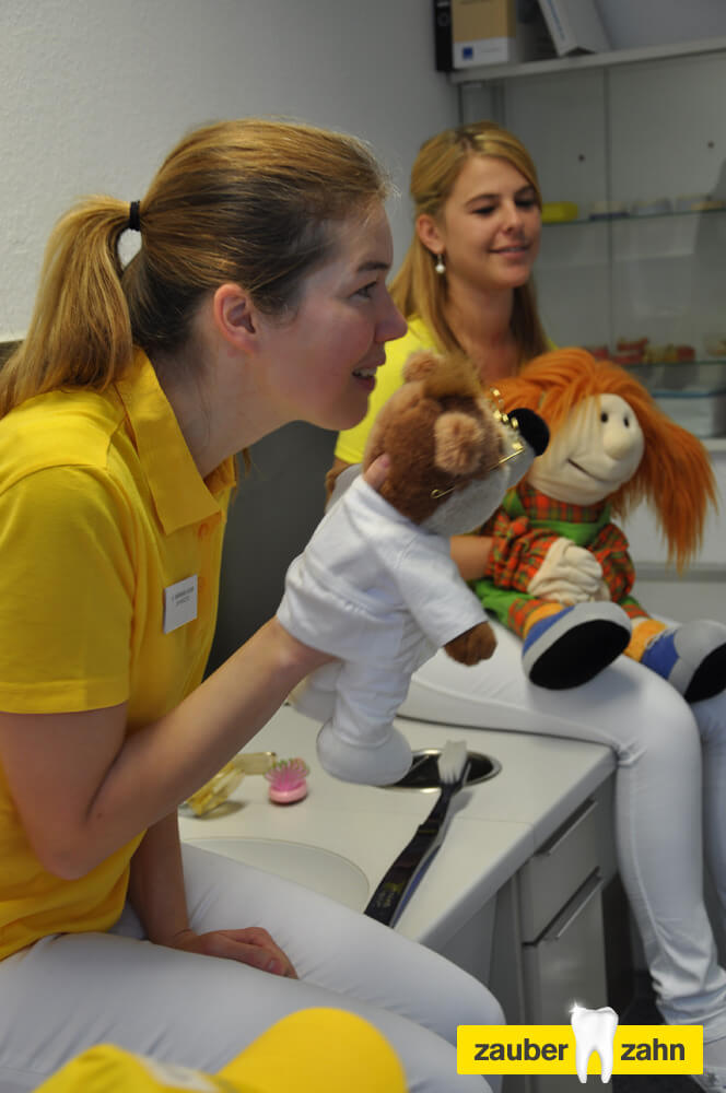 Mitarbeiterin spielt mit zwei Handpuppen vor Kindern.