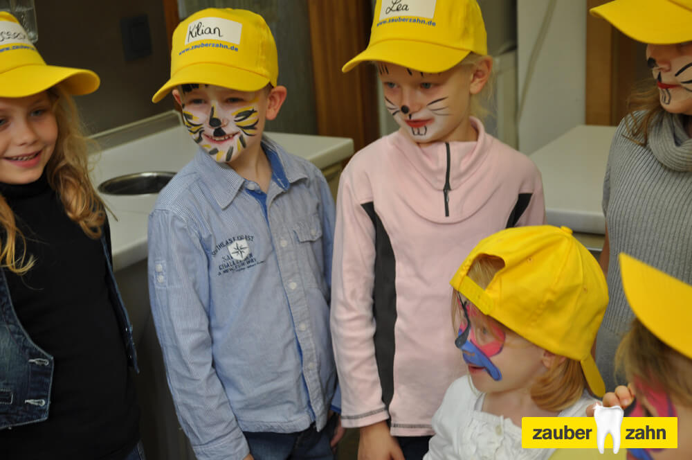 Kinder mit gelben Kappen und bunt bemalten Gesichtern.