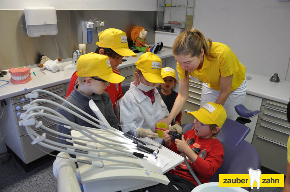 Mitarbeiterin zeigt mehreren Kindern etwas an der Behandlungseinheit.