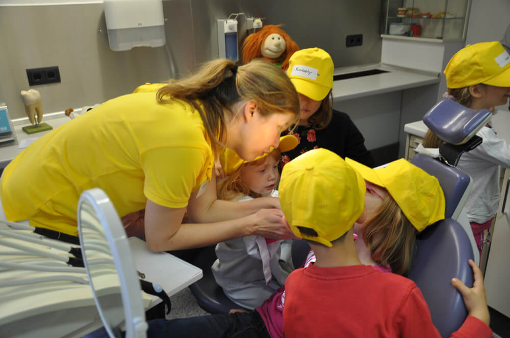 Mitarbeiterin zeigt Kindern etwas aus der Nähe.