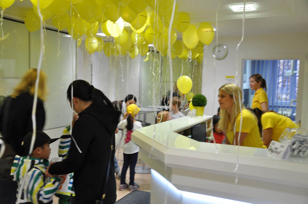 Empfangsbereich der Zahnarztpraxis mit gelben Luftballons und mehreren Personen.