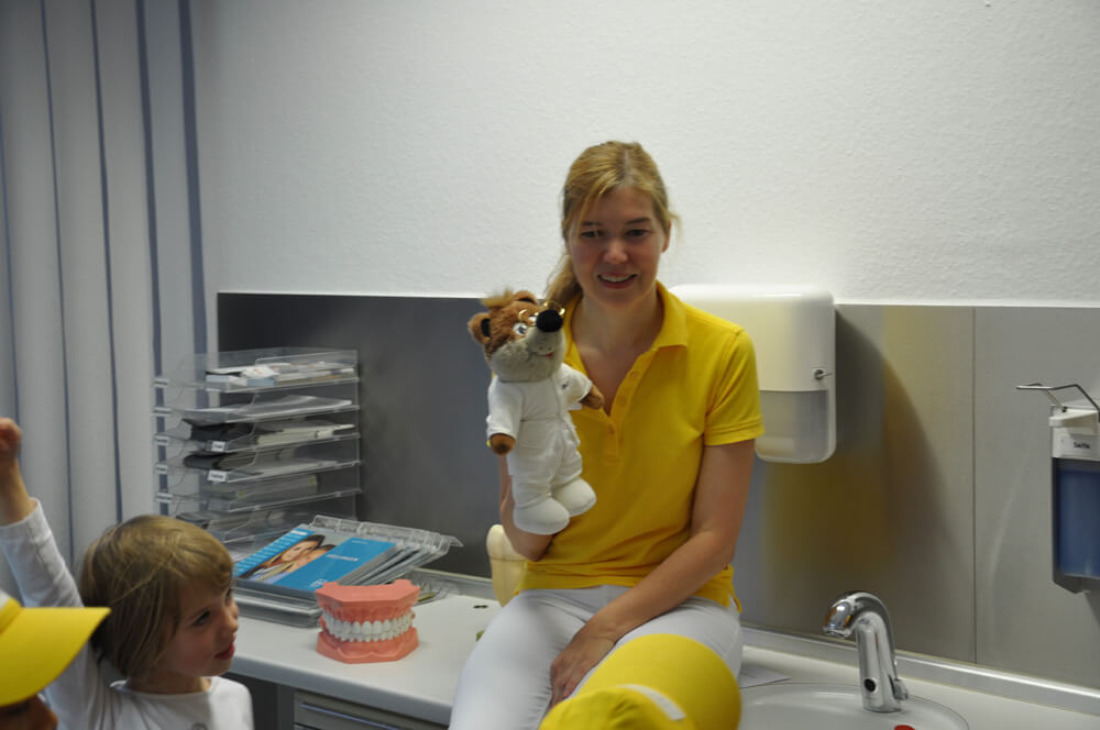 Mitarbeiterin sitzt mit einer Handpuppe im Behandlungszimmer.