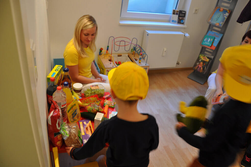 Mitarbeiterin spricht mit Kindern über Getränke und Snacks.