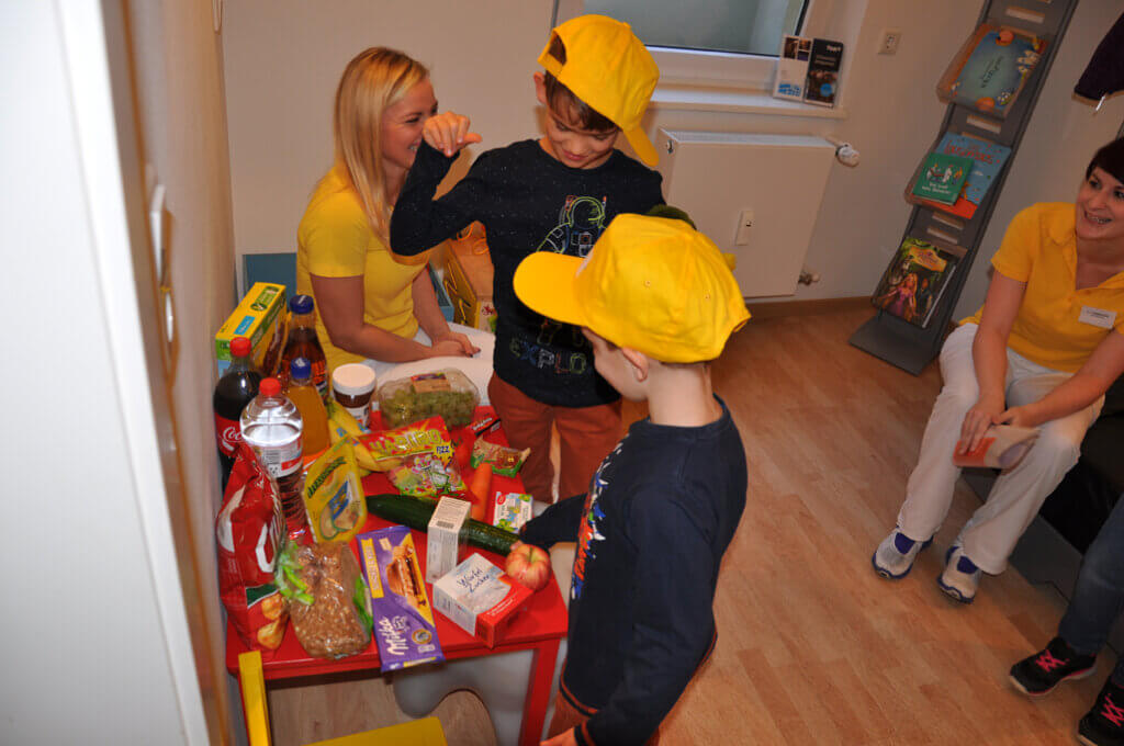 Mitarbeiterin spricht mit Kindern über Getränke und Snacks.