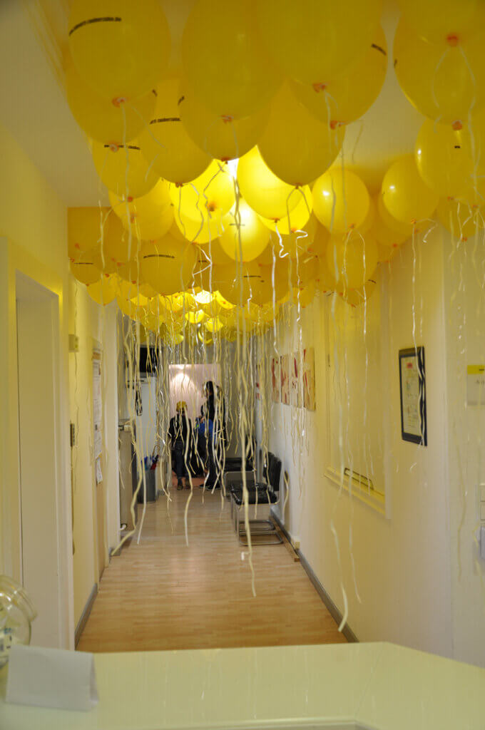 Flur der Zahnarztpraxis mit zahlreichen gelben Luftballons.
