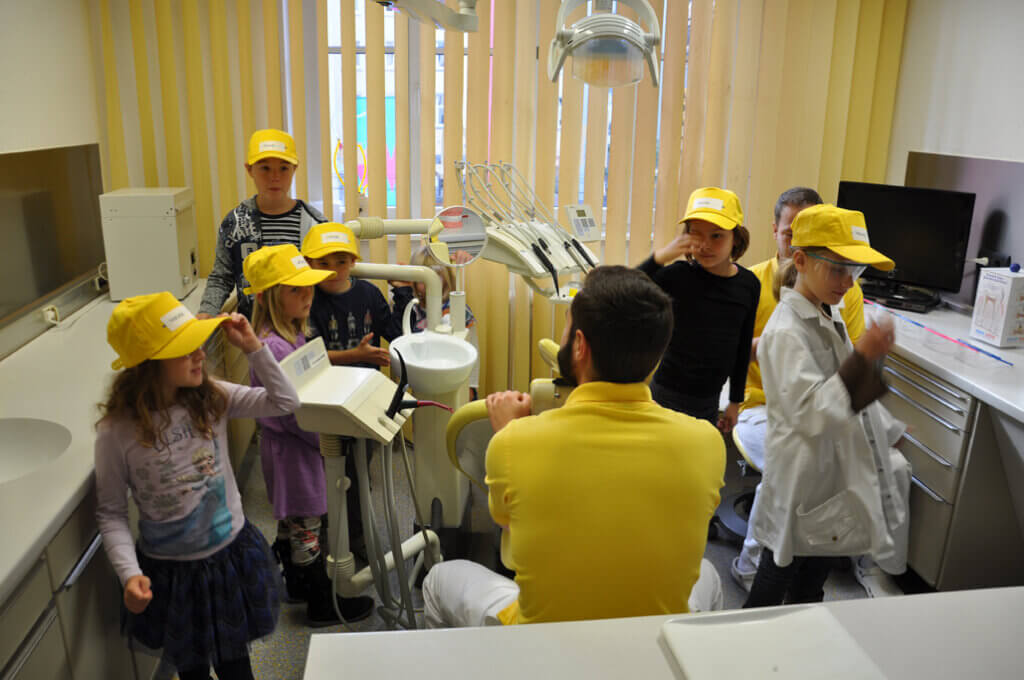 Mitarbeiter erklärt Kindern die zahnärztliche Behandlungseinheit.