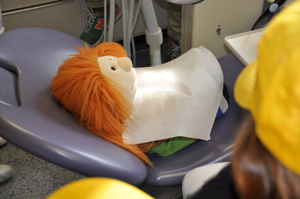 Handpuppe liegt auf einem zahnärztlichen Behandlungsstuhl.