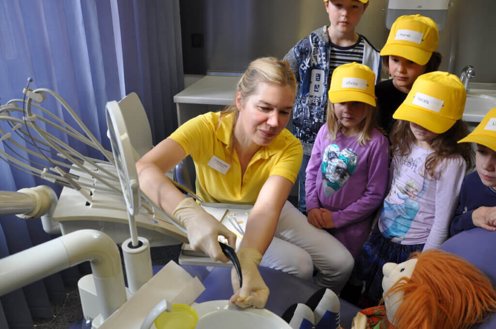 Mitarbeiterin zeigt Kindern eine Behandlungseinheit.