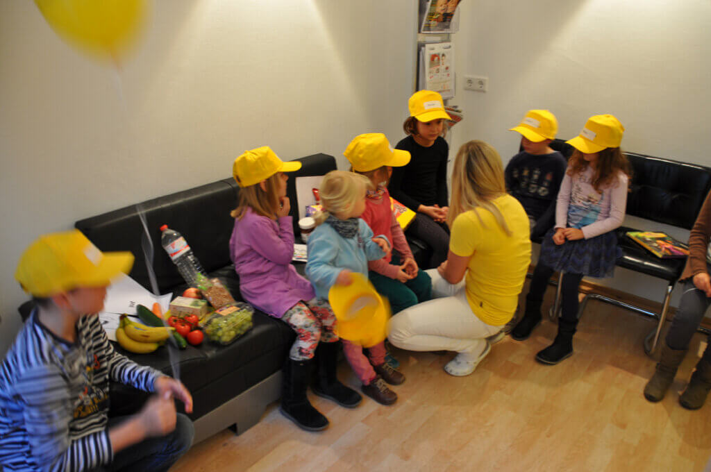 Mitarbeiterin betreut Kinder im Wartebereich.