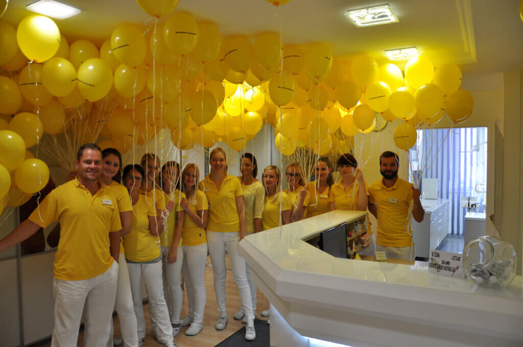 Praxisteam mit gelben Luftballons am Empfang.