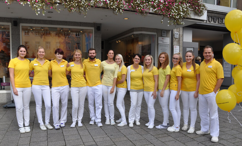 Praxisteam der Zahnarztpraxis vor dem Praxiseingang.