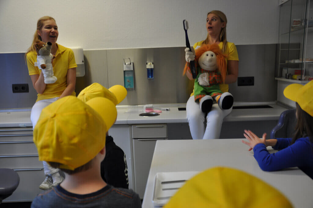 Mitarbeiterin spielen mit Kindern und Handpuppen im Behandlungszimmer.